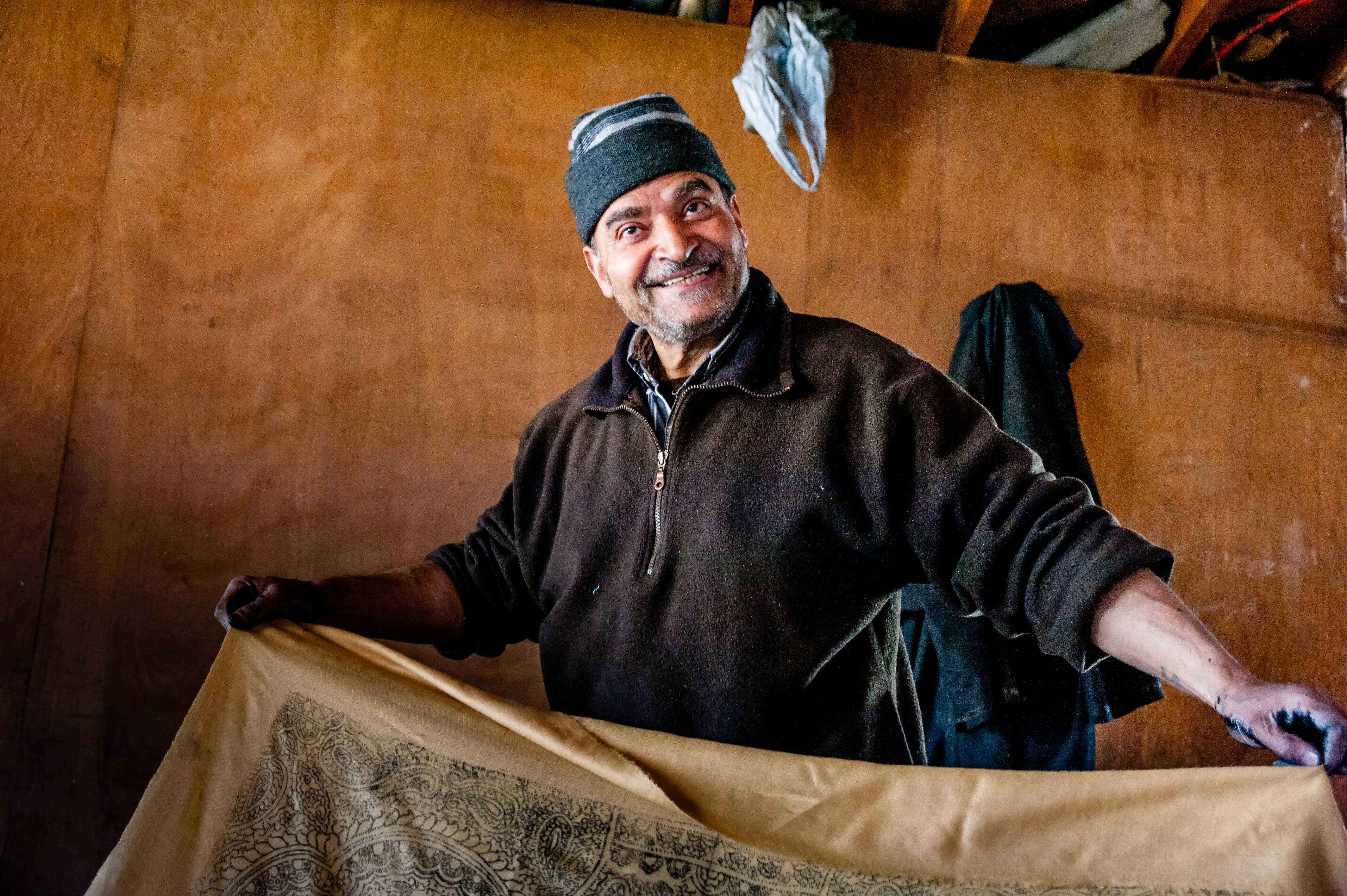 An artisan smiling while holding a hand block-printed shawl