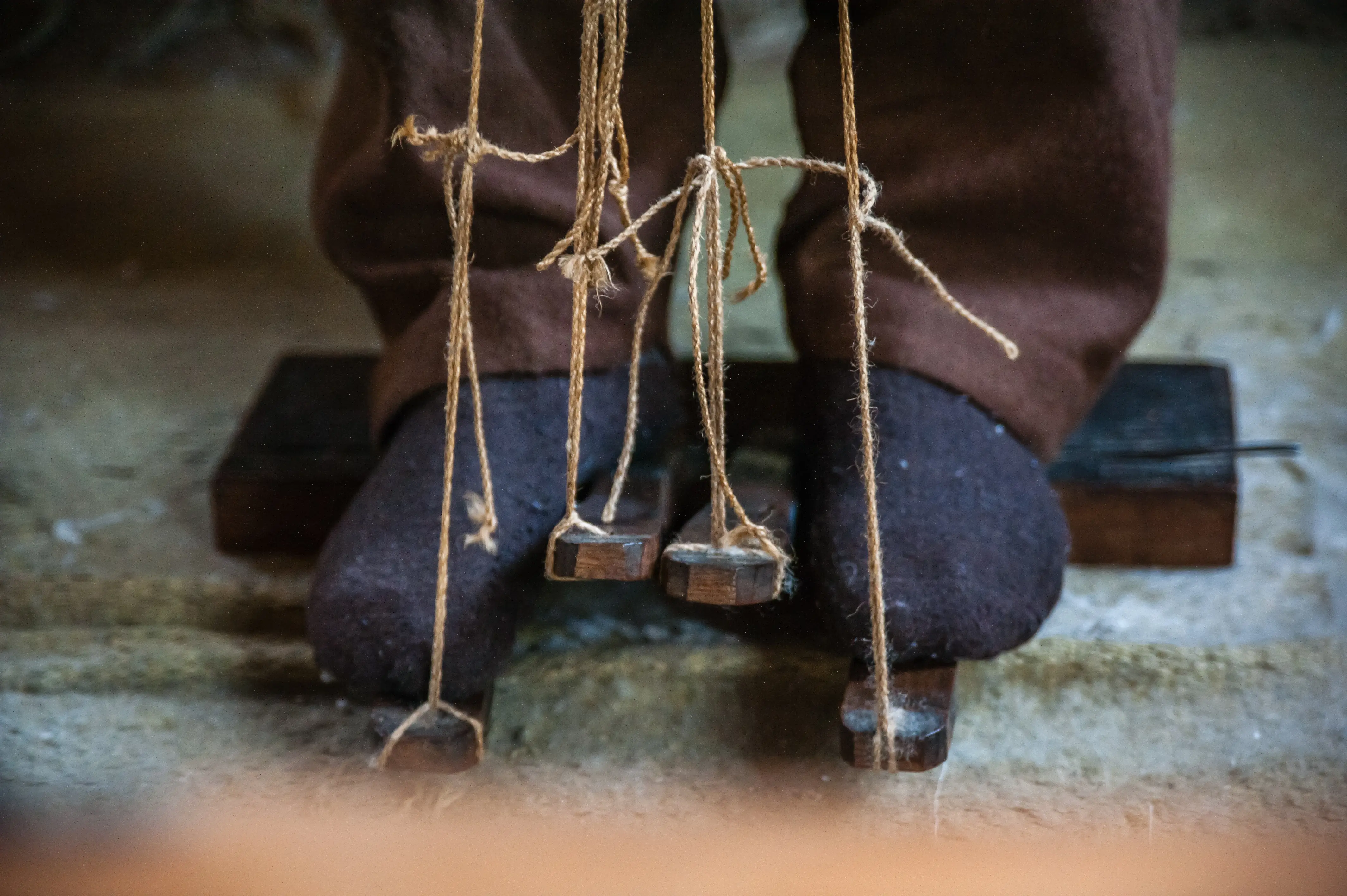 A close-up of a weaver's feet on the loom's wooden treadles