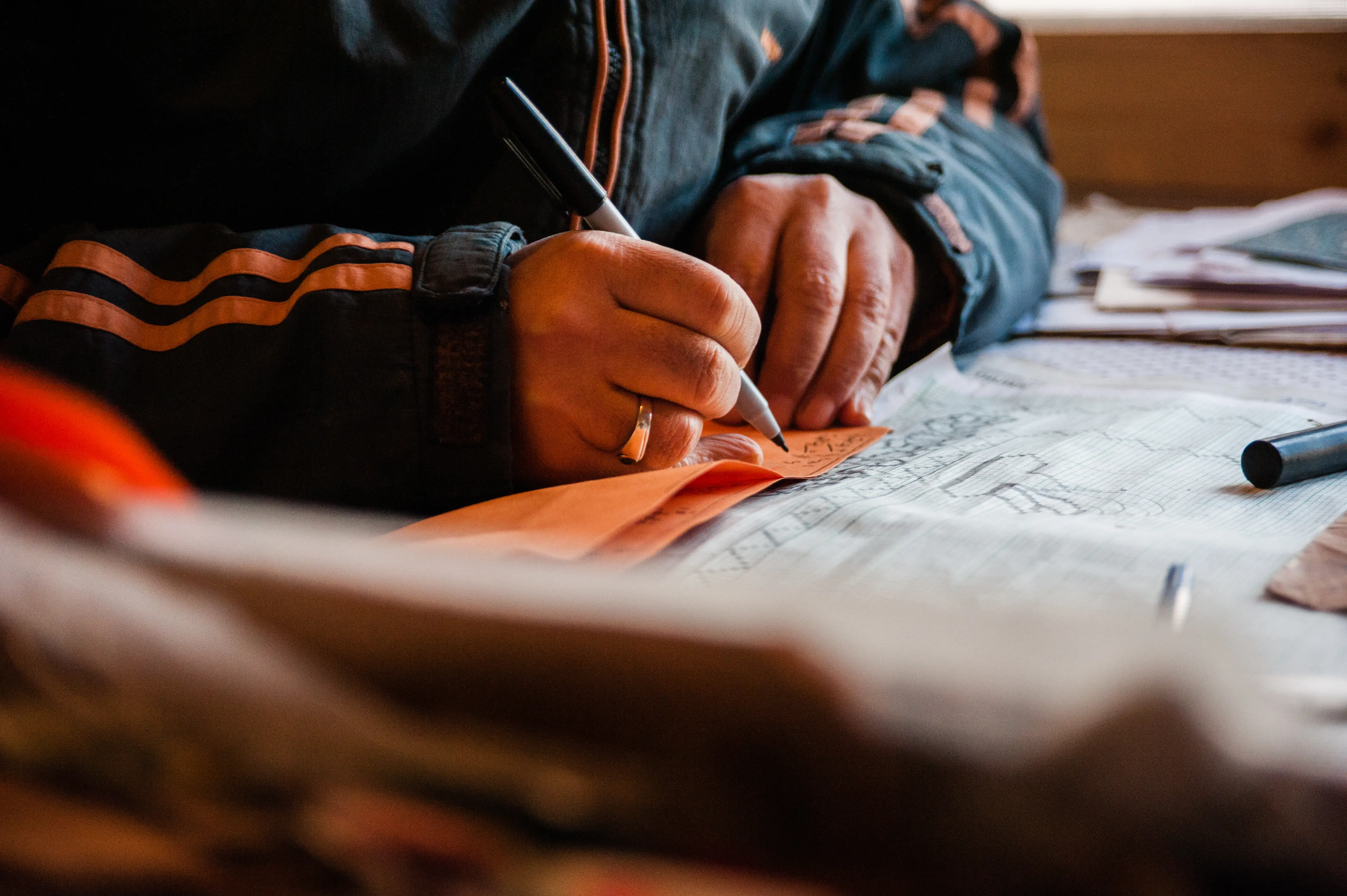 An artisan hand-marking a design onto graph paper before it goes to the loom