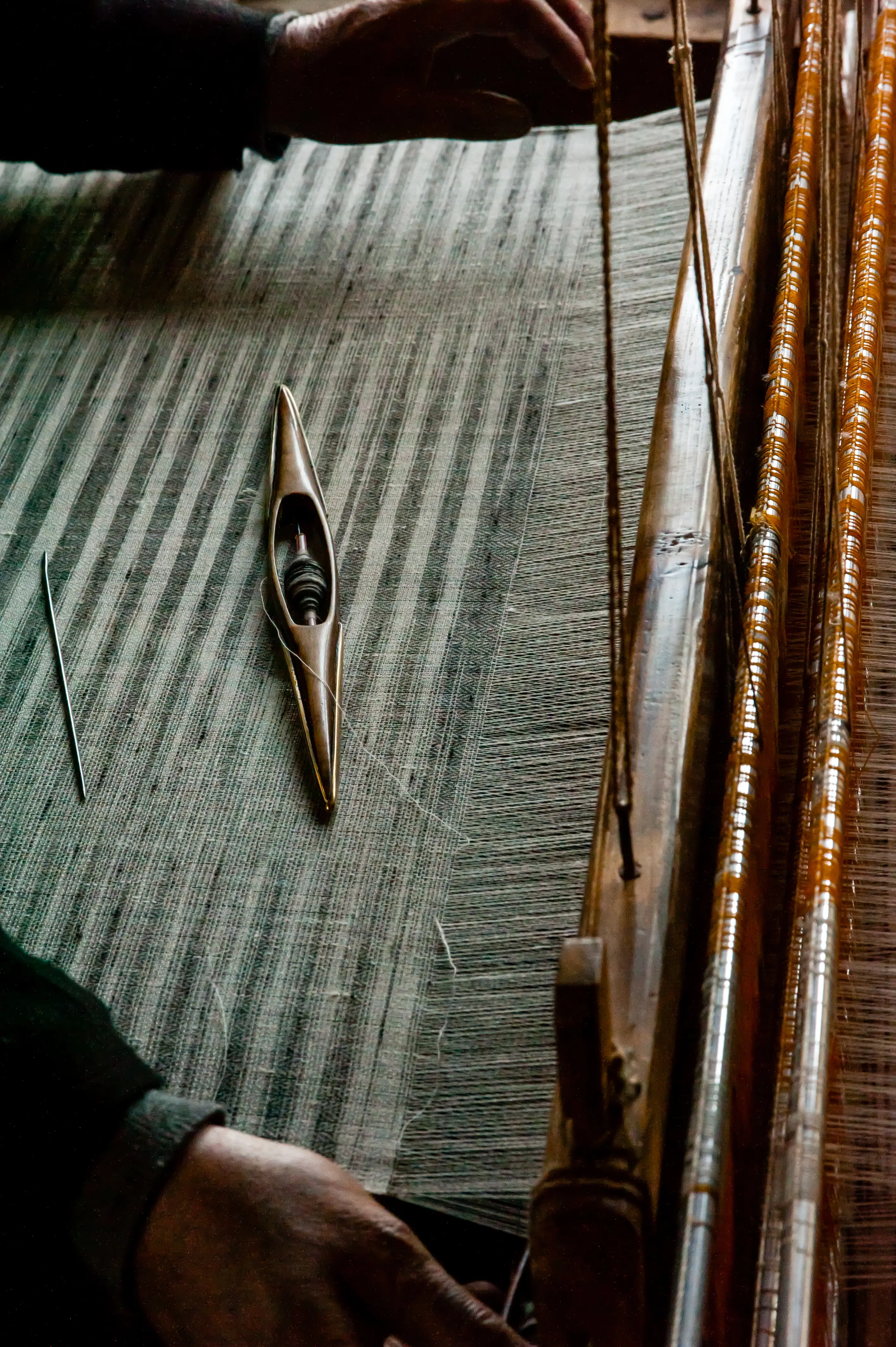 A weaving shuttle resting on freshly woven striped fabric