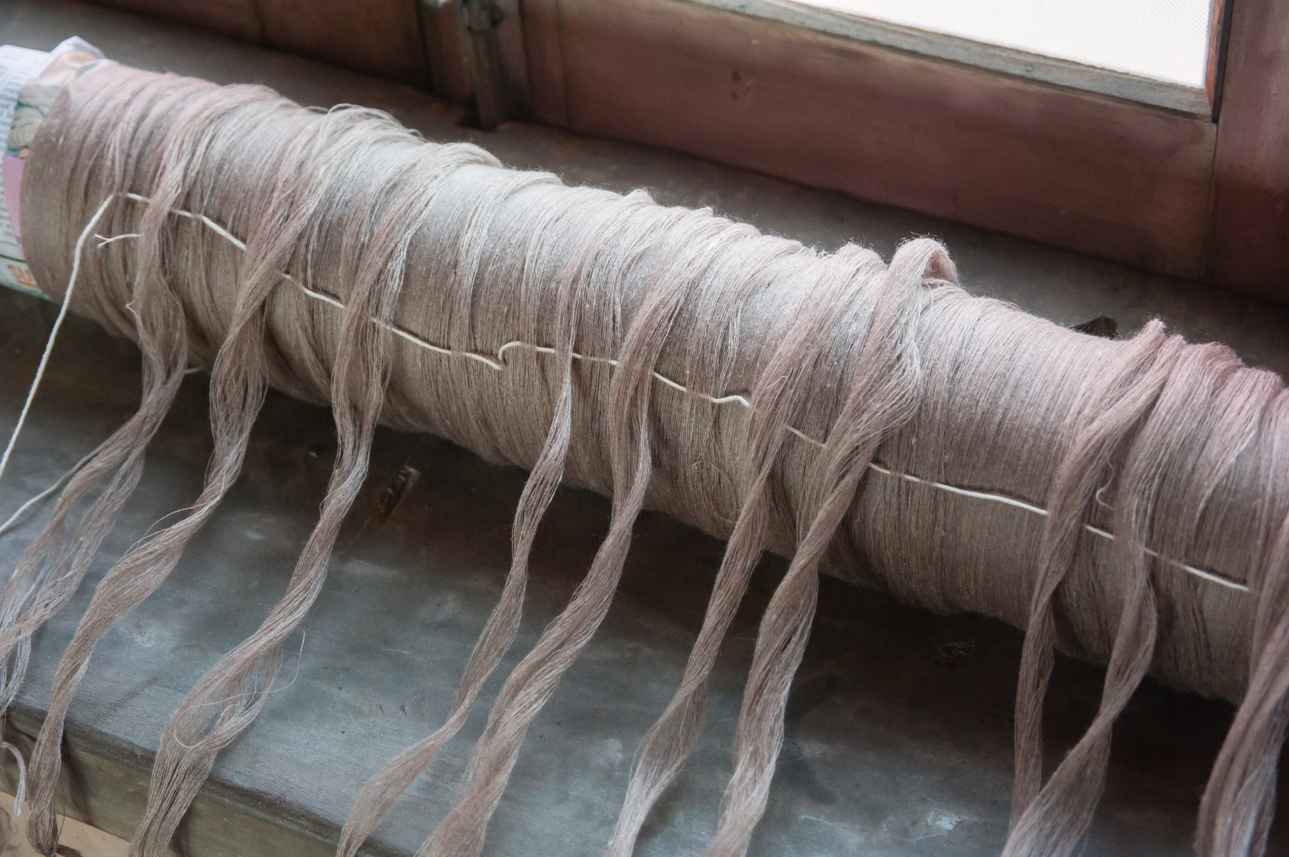 A warp beam wound with pale, hand-dyed yarn